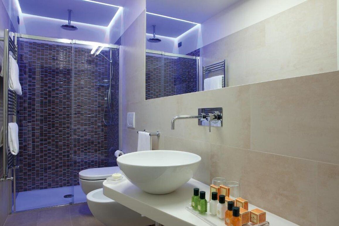 A modern bathroom with a large white sink, a glass shower enclosure, and a mirror above the sink.