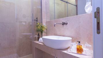 A modern bathroom with a large white sink, a glass shower enclosure, and a mirror above the sink.
