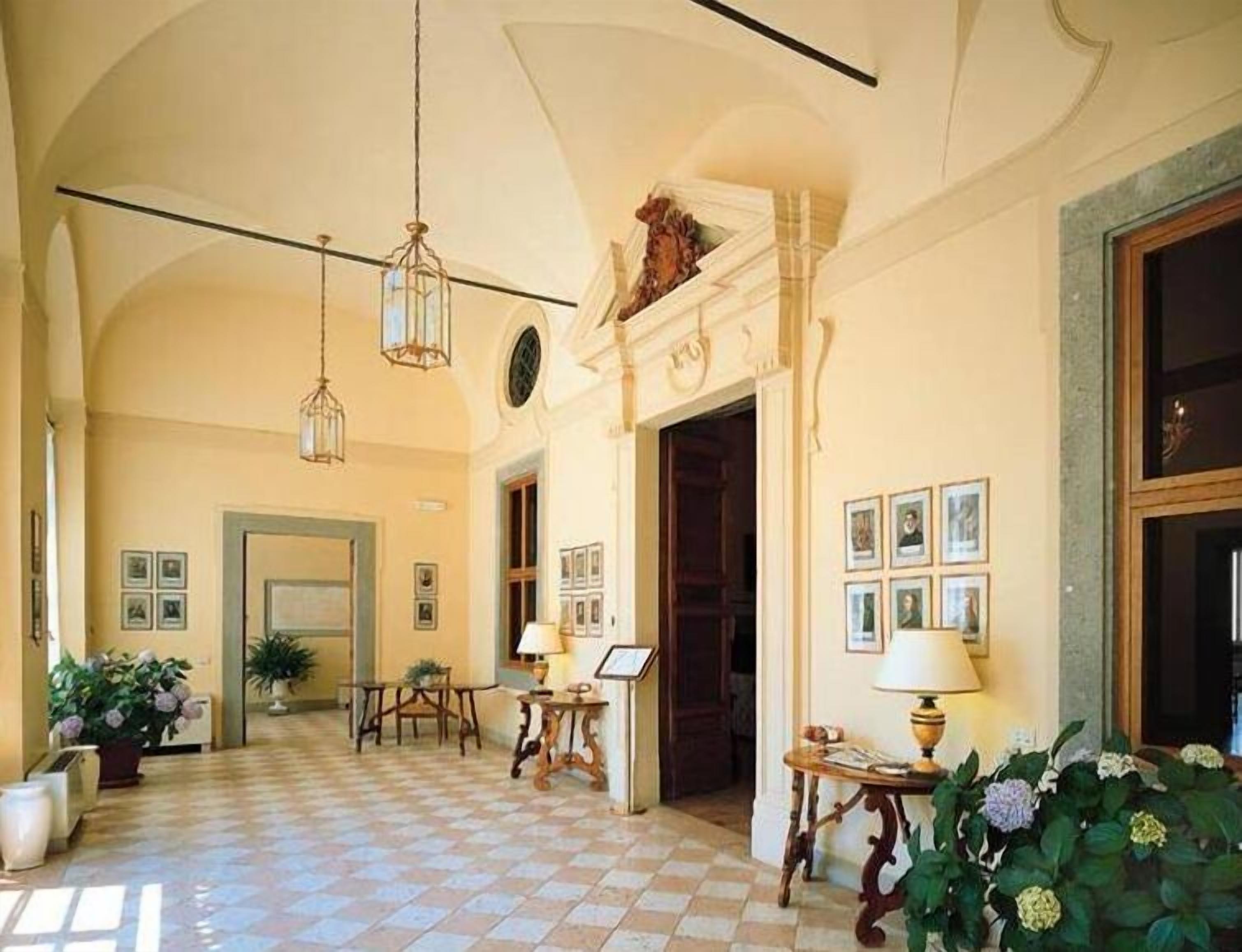 A spacious lobby with a checkered floor, hanging lights, and framed pictures on the walls.