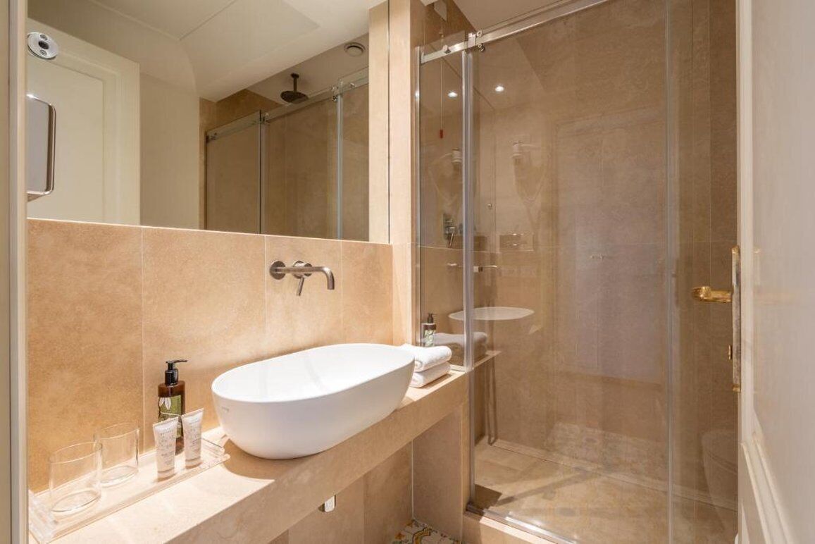 Une salle de bain moderne avec un grand lavabo blanc, une cabine de douche en verre et un miroir au-dessus du lavabo.