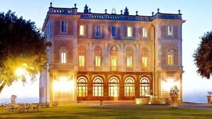 Un grand bâtiment de style classique, doté de nombreuses fenêtres et d’une façade symétrique, qui pourrait être un hôtel ou un bâtiment public.