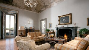 Amplia sala de estar con chimenea, sofás a rayas y un candelabro.