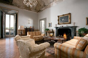 Amplia sala de estar con chimenea, sofás a rayas y un candelabro.