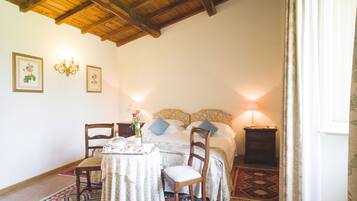Una camera da letto con soffitto in legno, un letto con cuscini, un comodino con una lampada e una sedia.