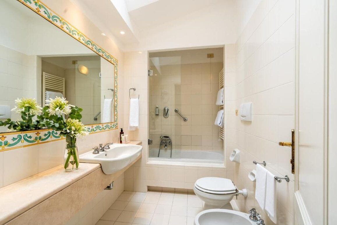 A modern bathroom with a double sink, a bathtub, and a toilet.