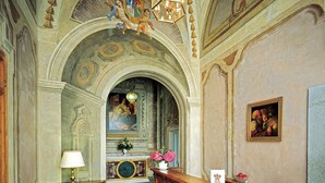Un interior ornamentado con un arco alto, una araña y un cuadro en la pared.