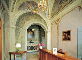 Un interior ornamentado con un arco alto, una araña y un cuadro en la pared.