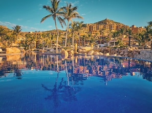 A resort with a clear pool, palm trees, and a mountain backdrop. - Grand Fiesta Americana Los Cabos All Inclusive Golf & Spa (Cabo San Lucas)