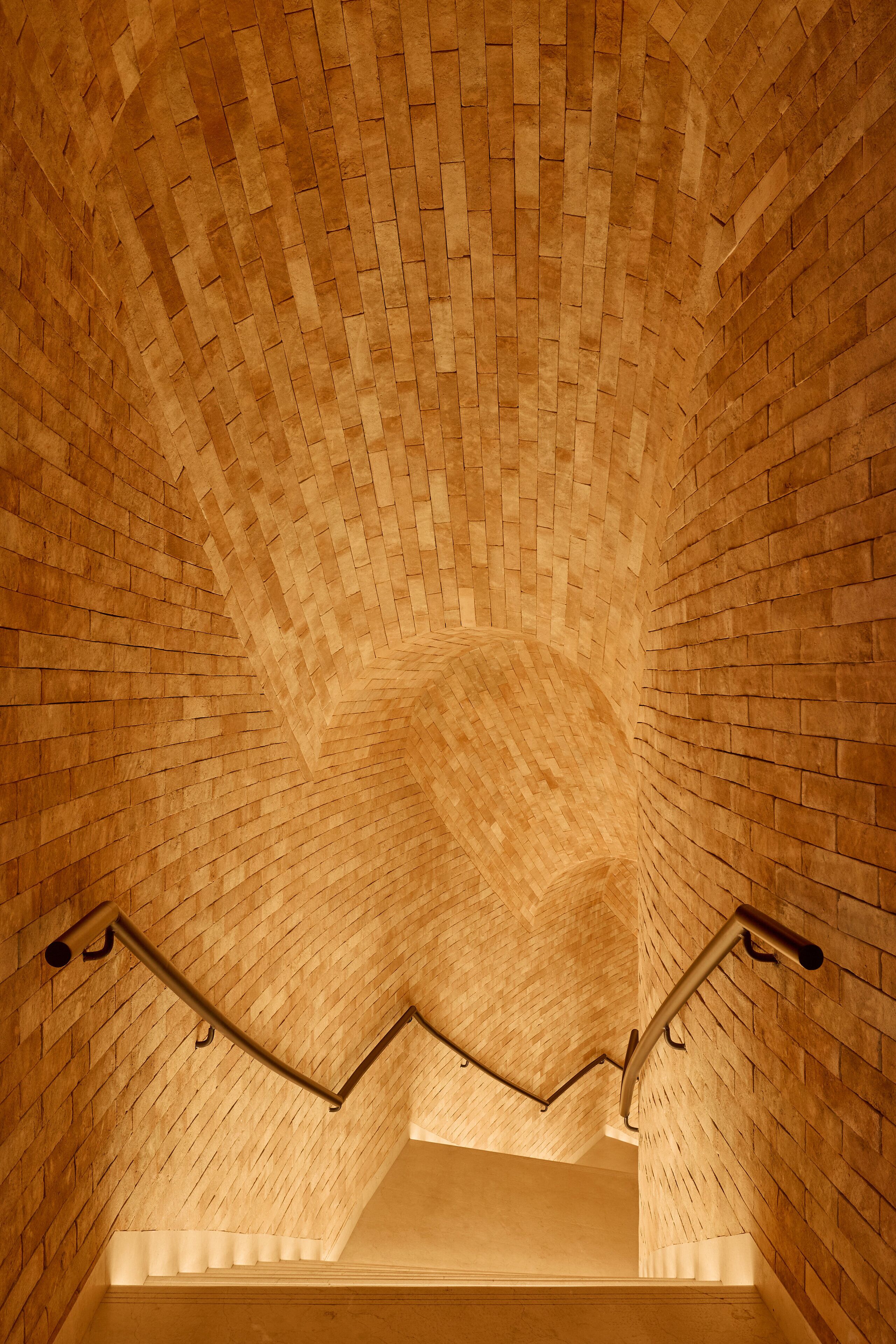 A brick-walled staircase with a handrail.