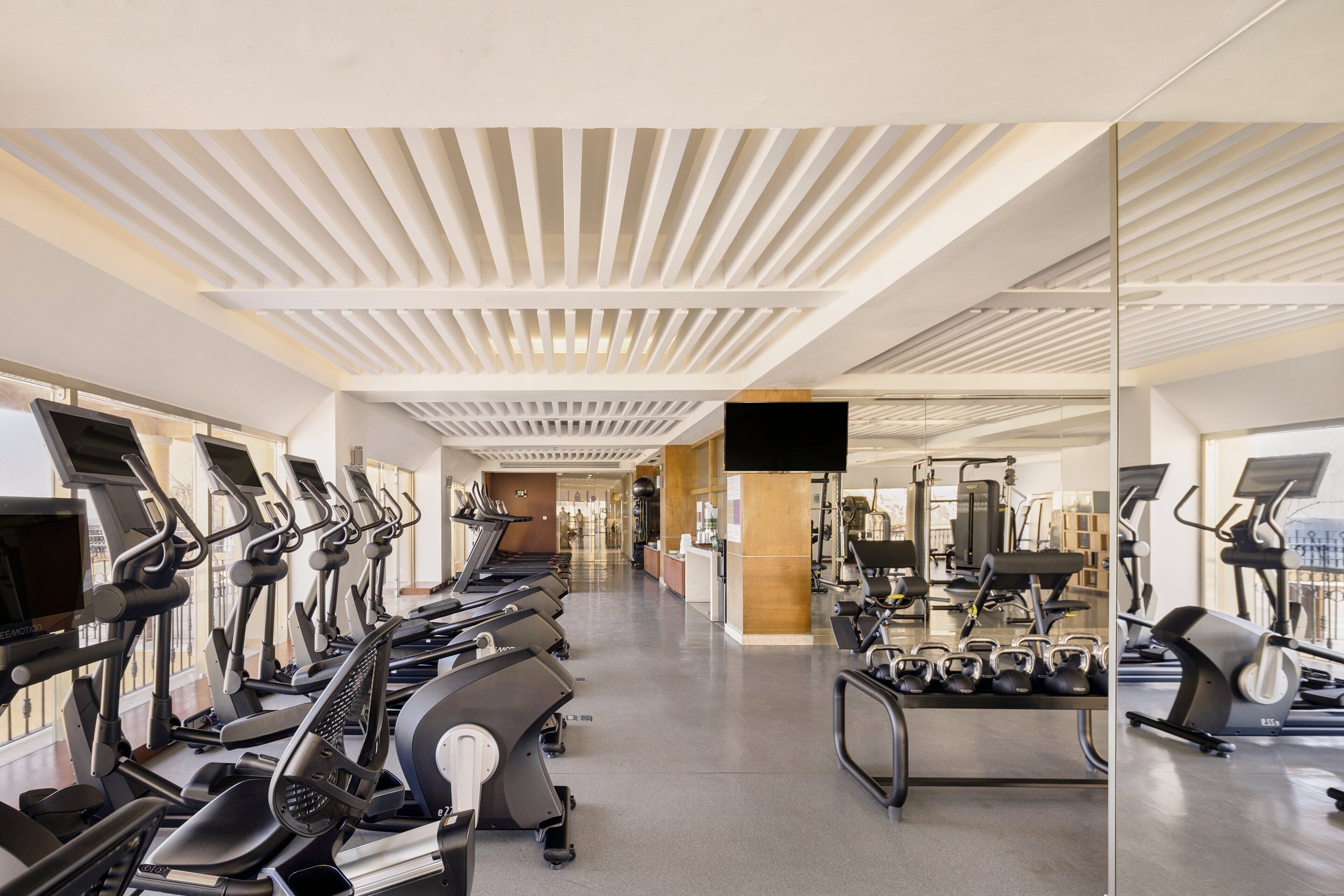 A modern gym with rows of treadmills, stationary bikes, and weight machines.