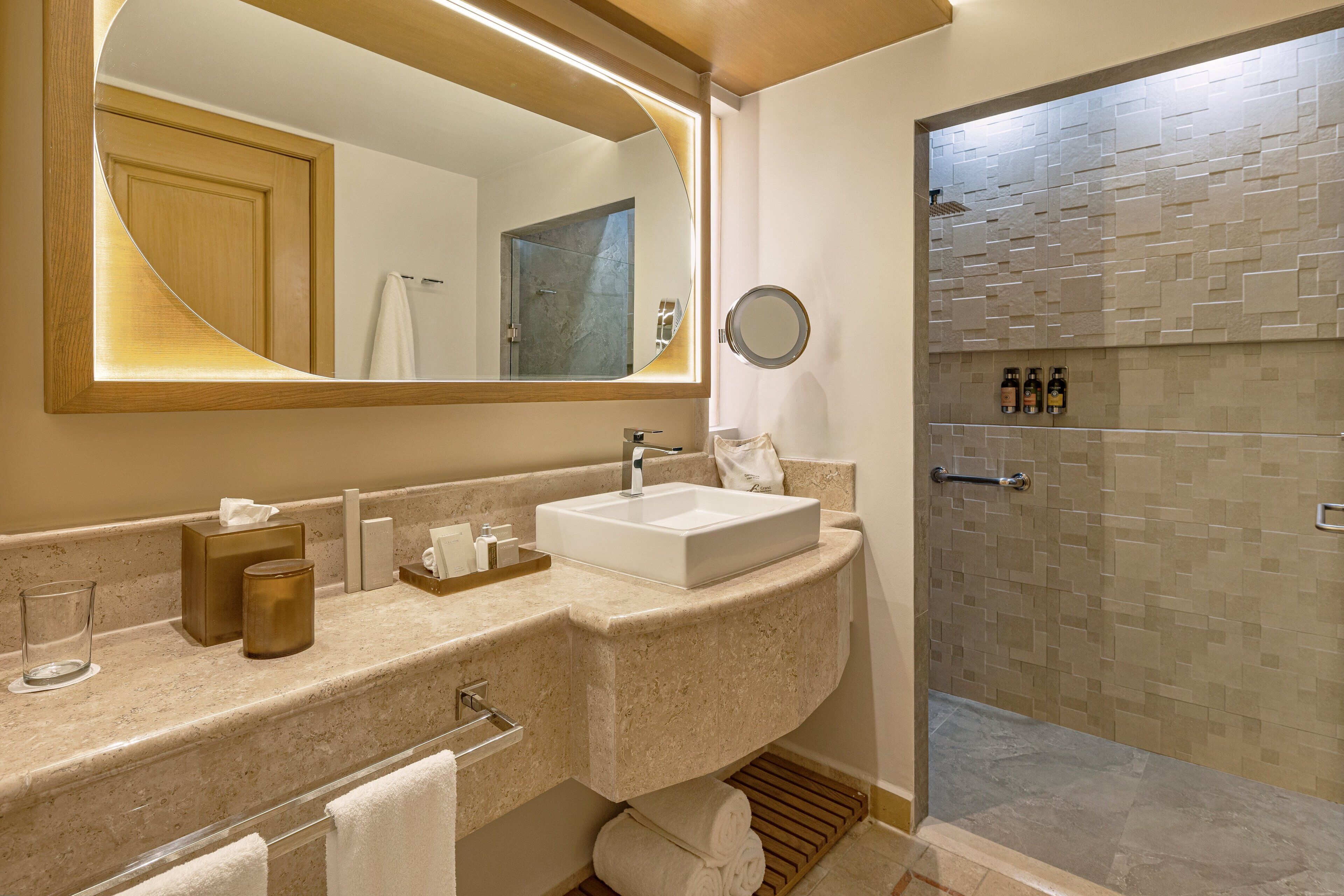 Un baño con un espejo grande, un lavabo y zona de ducha.