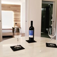 Una habitación de hotel con una mesa redonda, dos copas de vino y una botella de vino Merlot de Umbria.