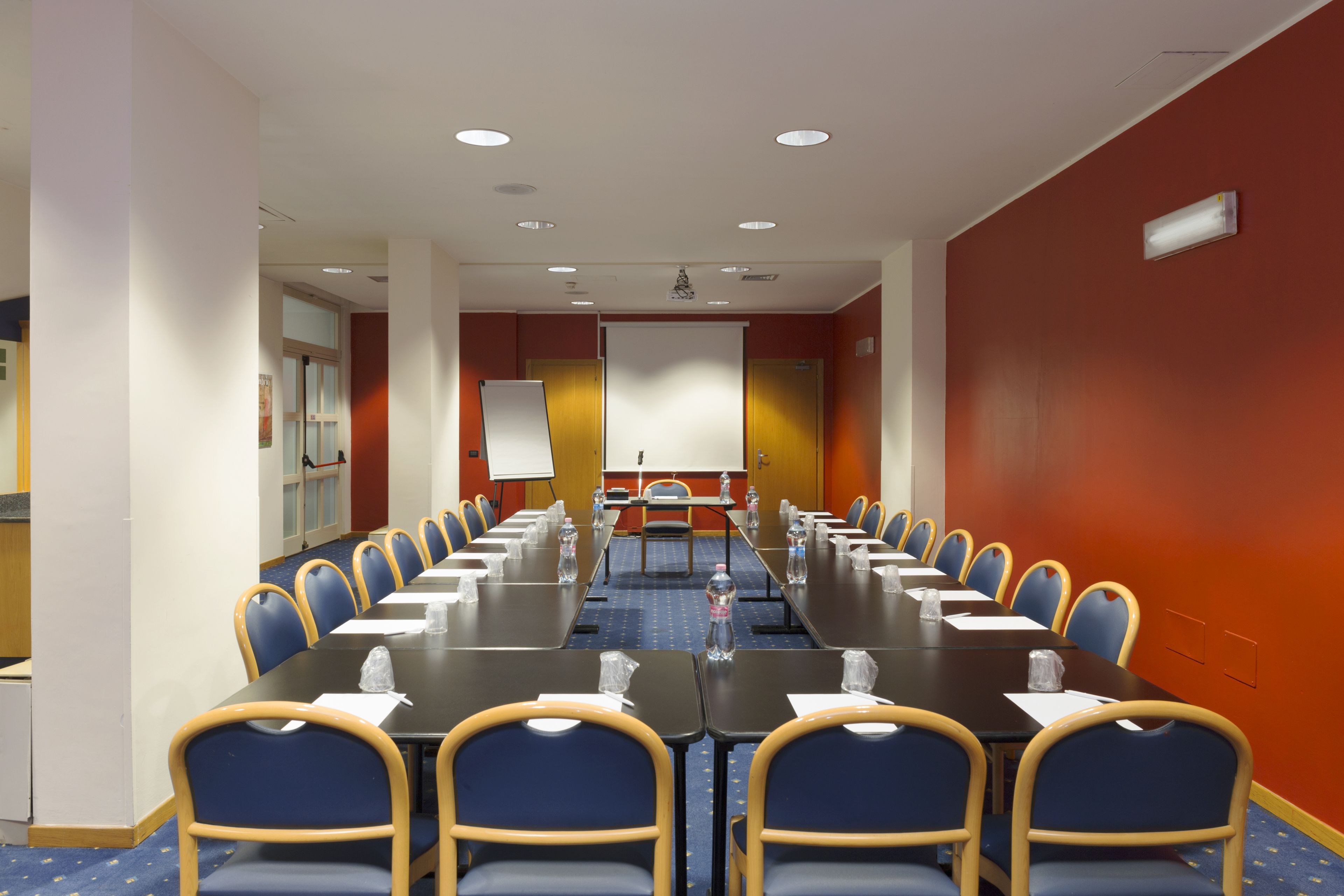 A conference room with a long table, blue chairs, and a whiteboard at the front.