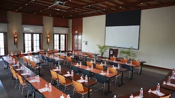 Un salón de conferencias con varias mesas y sillas, equipado con botellas de agua y tarjetas de identificación.