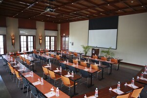 Un salón de conferencias con varias mesas y sillas, equipado con botellas de agua y tarjetas de identificación.