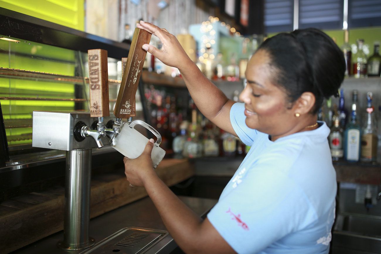 A bartender pouring a drink from a tap labeled "SANDS."