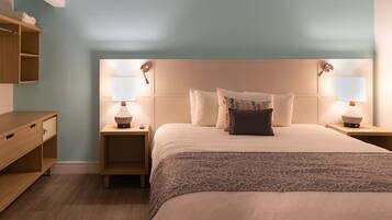 Un dormitorio ordenado con cama, mesitas de noche y una mesita auxiliar de madera.