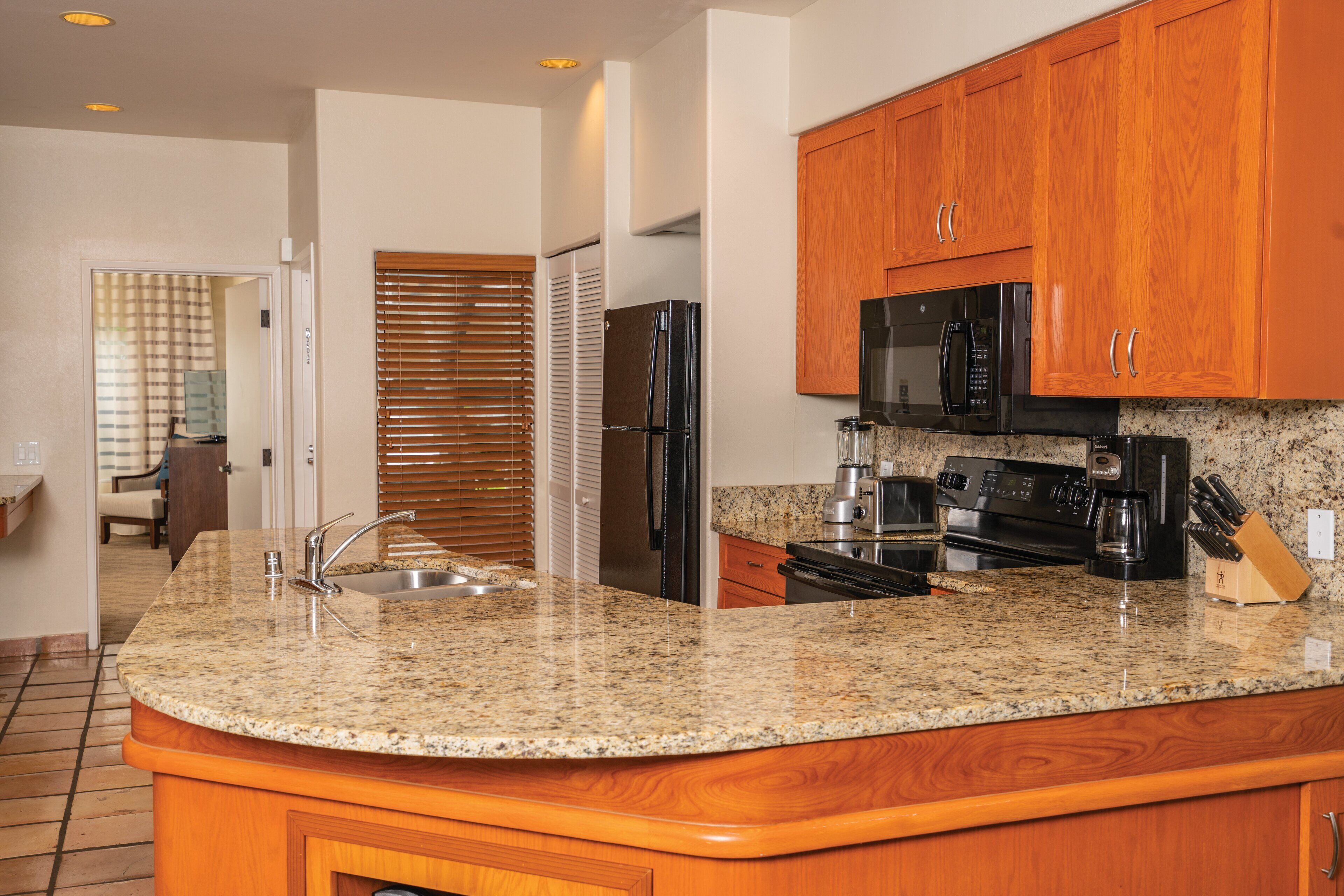 A kitchen with granite countertops, wooden cabinets, stainless steel appliances, and a built-in oven.