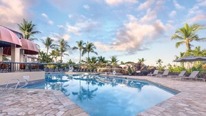 A swimming pool with lounge chairs and umbrellas, surrounded by palm trees and a clear sky. - Kona Coast Resort (Kailua-Kona)