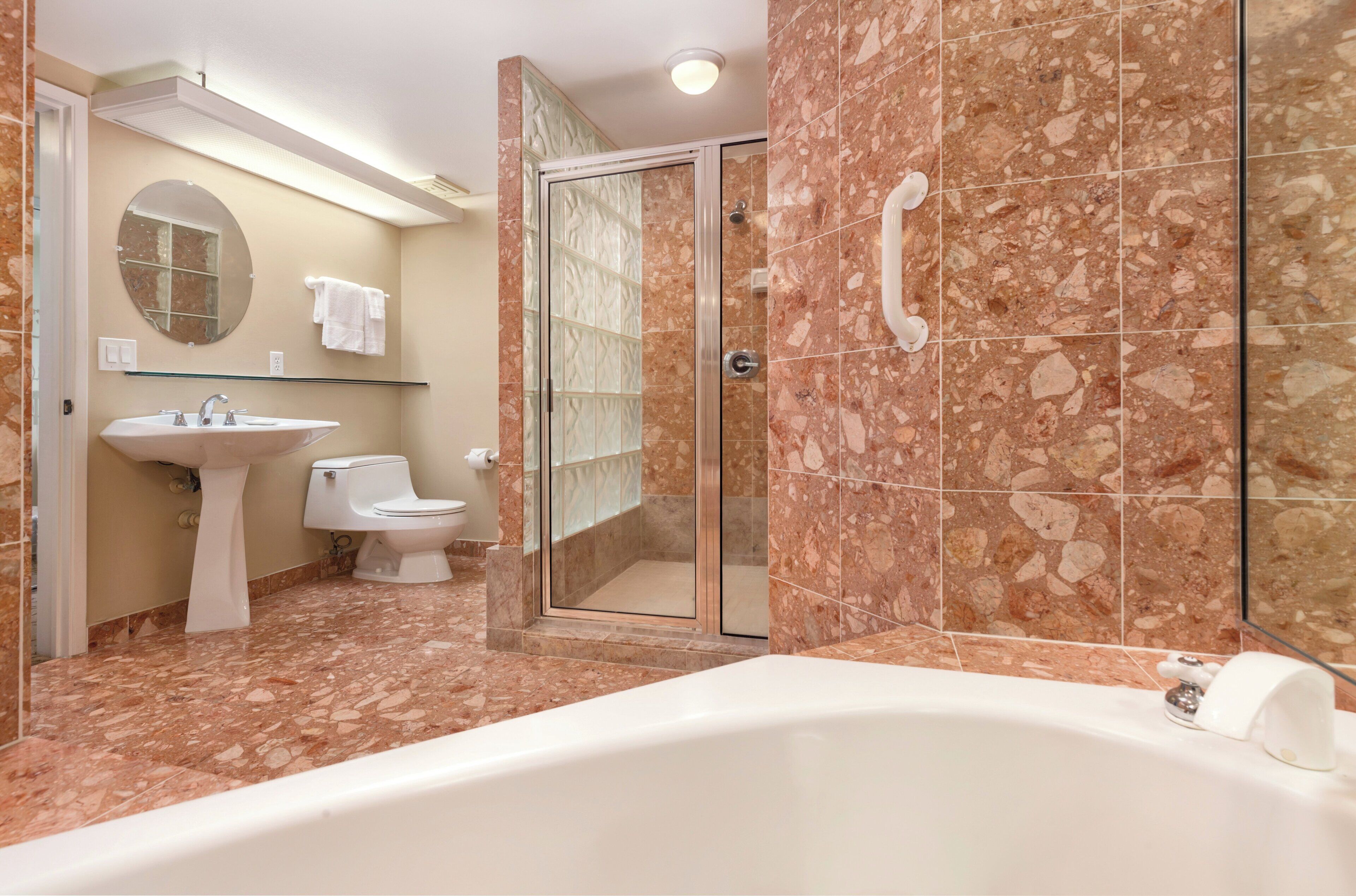 Un baño con bañera, lavamanos, inodoro y ducha con mampara de vidrio.