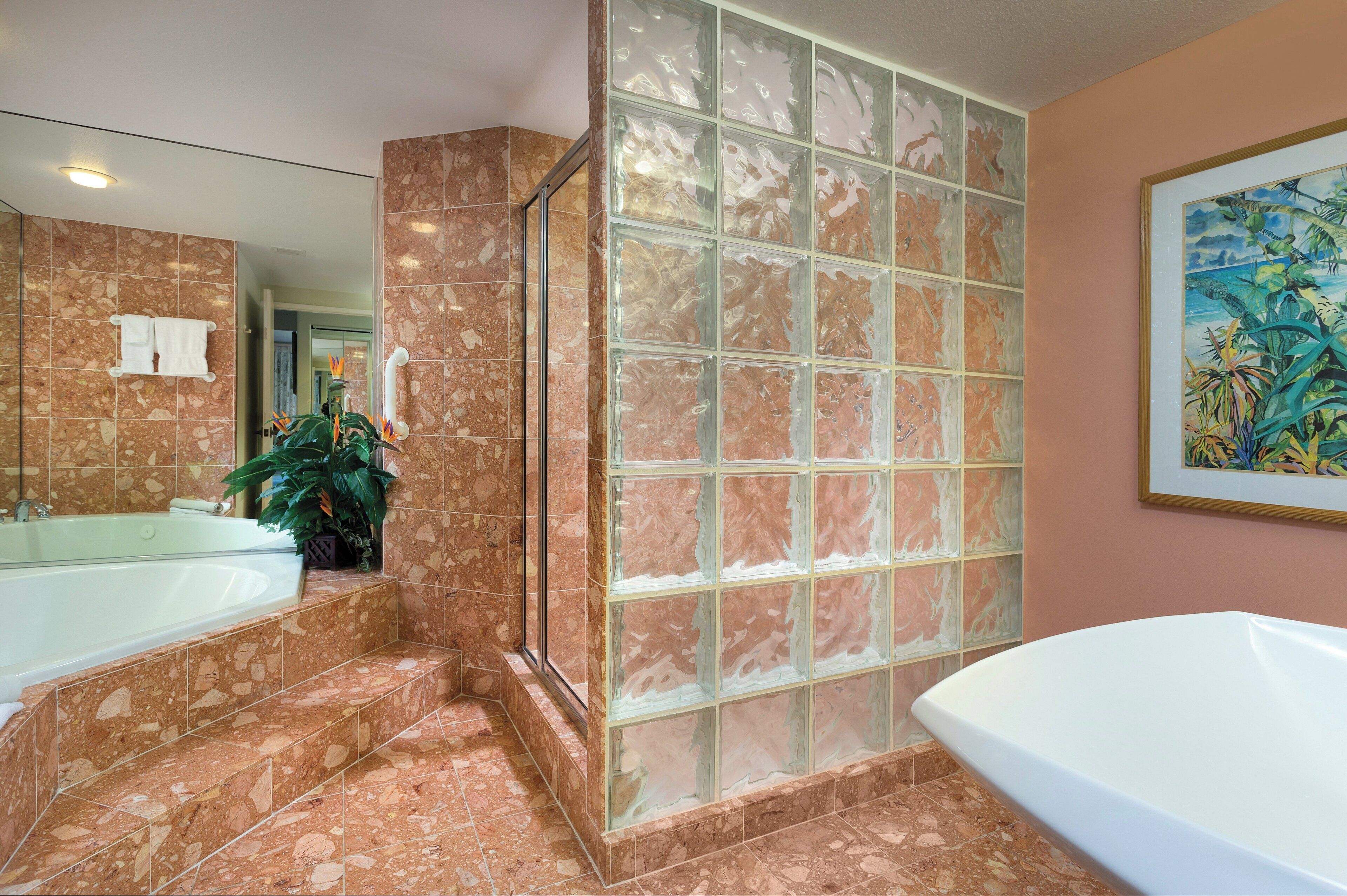 A bathroom with a large bathtub, a glass shower enclosure, and a marble-tiled floor.
