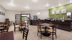 A modern cafe with wooden tables and chairs, a counter with a coffee machine, and artwork on the walls. - Sleep Inn Athens I-65 (Athens)