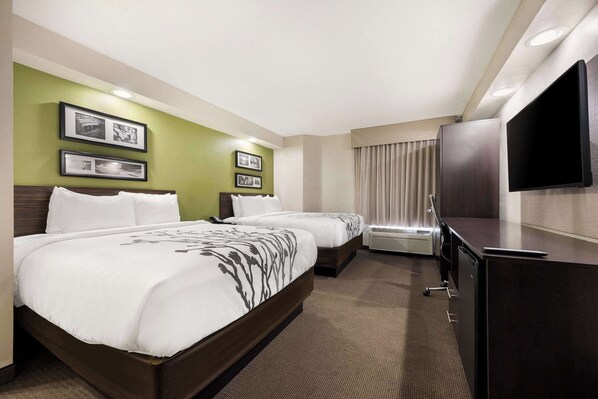 A hotel room with two beds, a flat-screen TV, and framed pictures on the wall.