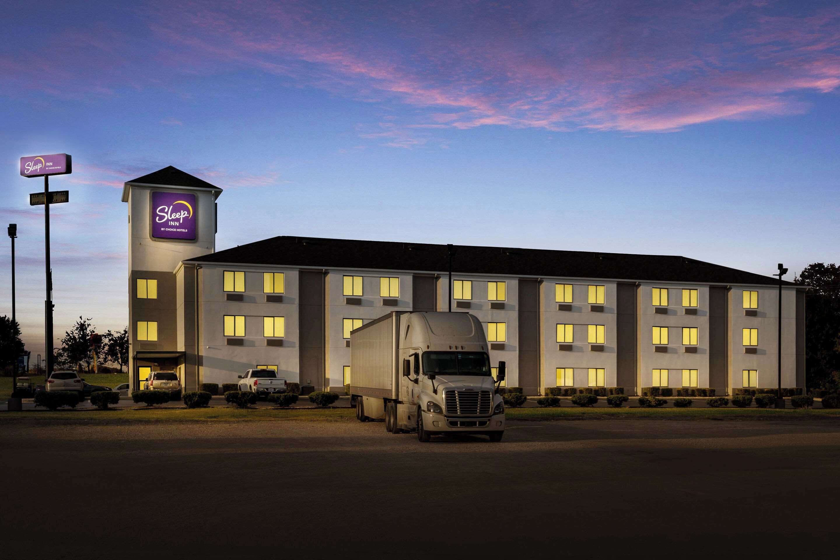 A Sleep Inn hotel with a large truck parked in front, multiple windows, and a signboard.
