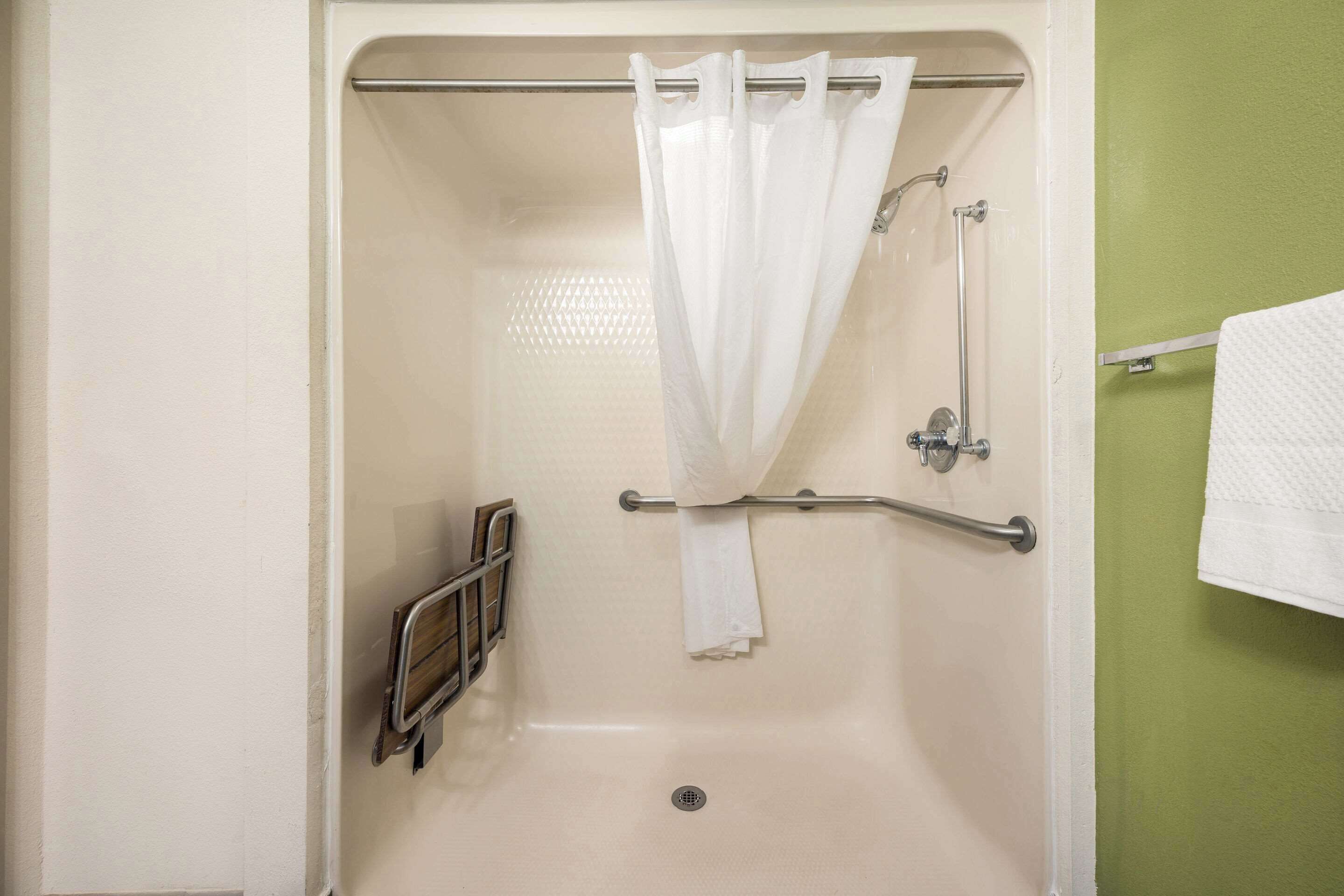 A bathroom with a bathtub, a shower curtain, a grab bar, and a towel rack.