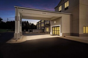 A modern building with a covered entrance, numbered 1115, and a well-lit facade.