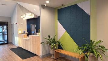 A reception area with a wooden desk, a bench, and potted plants.