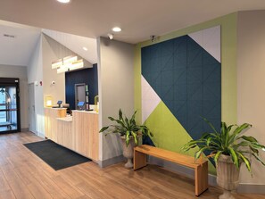 A reception area with a wooden desk, a bench, and potted plants.