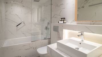 Un baño moderno con ducha de vidrio, un lavabo blanco y un inodoro.