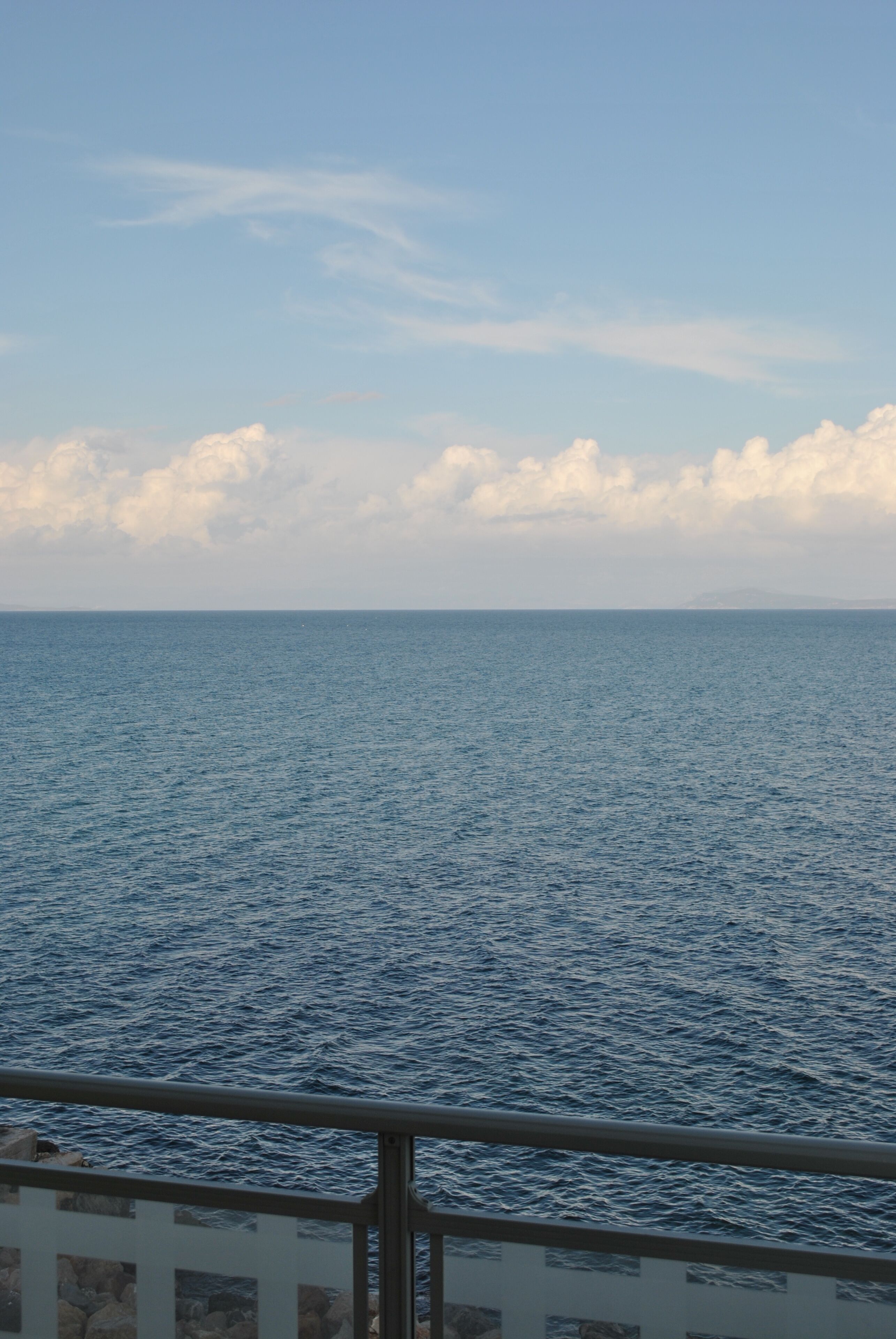 Vista do mar a partir de uma varanda com grade de metal.