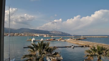 A marina with boats, a lighthouse, and a mountainous backdrop.