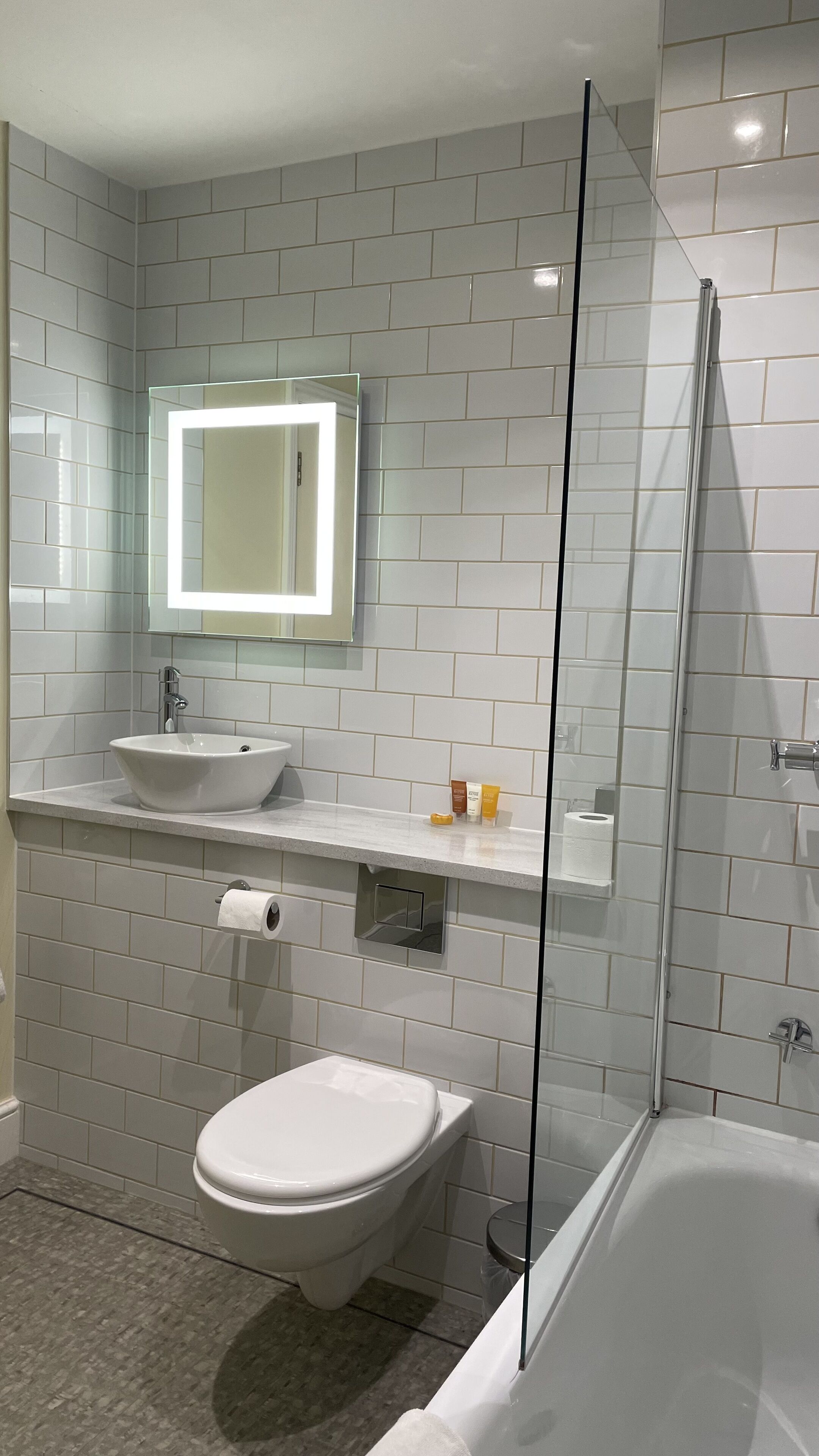 A modern bathroom with a glass-enclosed shower, a white sink, and a toilet.
