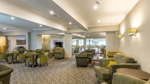 A spacious lobby with multiple seating areas, a fireplace, and a view of the dining area. - Hellidon Lakes Golf & Spa Hotel (Daventry)