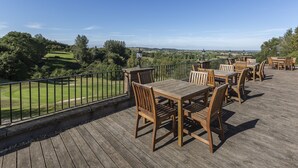 A wooden deck with outdoor seating overlooking a golf course. - Hellidon Lakes Golf & Spa Hotel (Daventry)