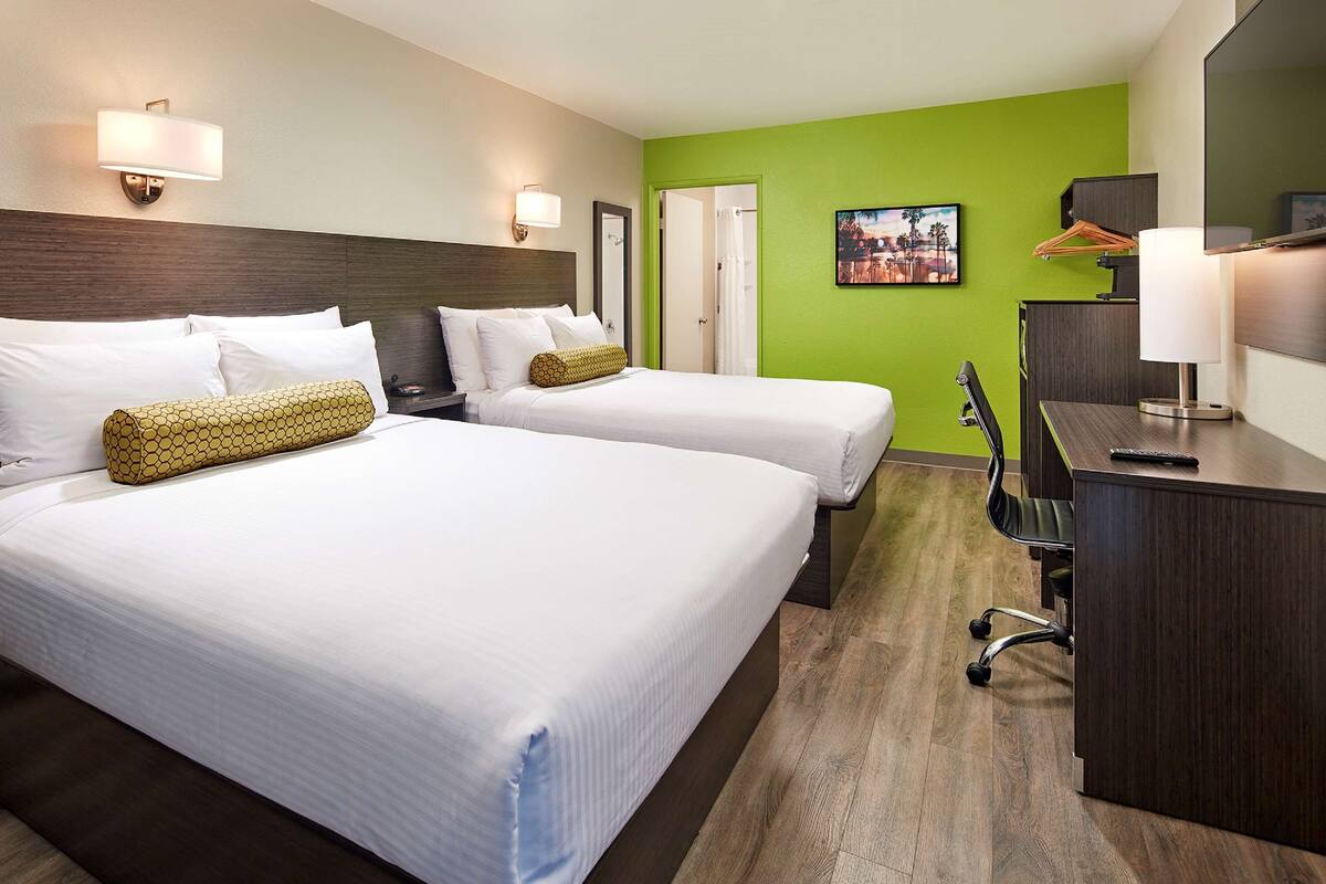 Ein Hotelzimmer mit zwei Betten, einem Schreibtisch und einem Stuhl.