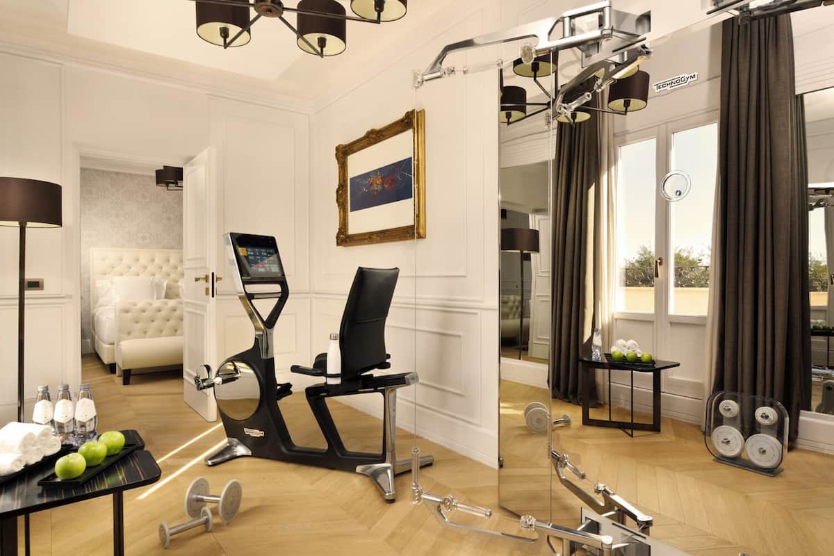 Ein Hotelzimmer mit Fitnessbereich, einschließlich Fahrradergometer, Hanteln und Spiegel.