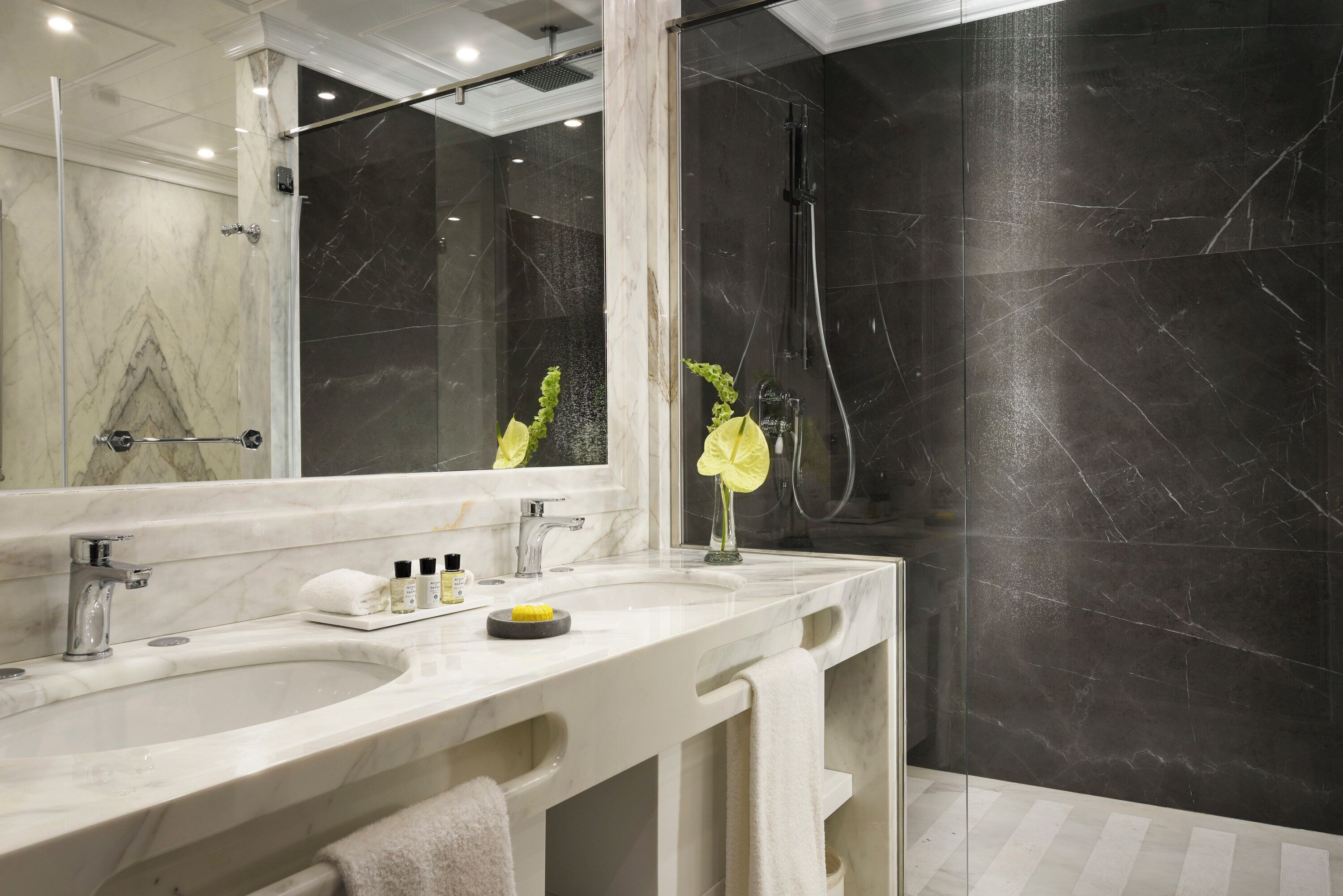 A bathroom with two sinks, a large mirror, and a shower area.