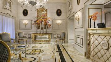 A luxurious lobby with ornate chandeliers, elegant furniture, and a marble floor.