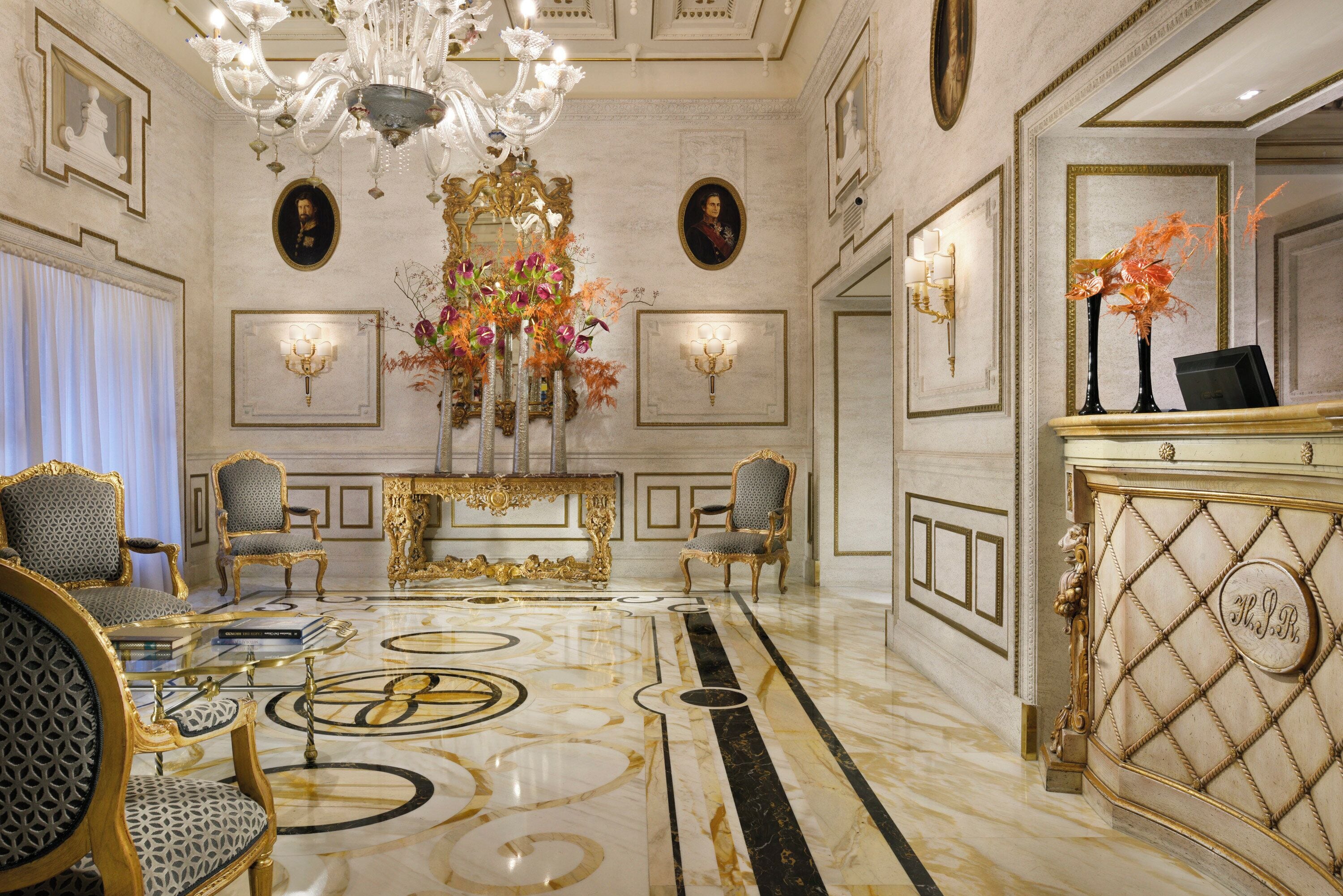 A luxurious lobby with ornate chandeliers, elegant furniture, and a marble floor.