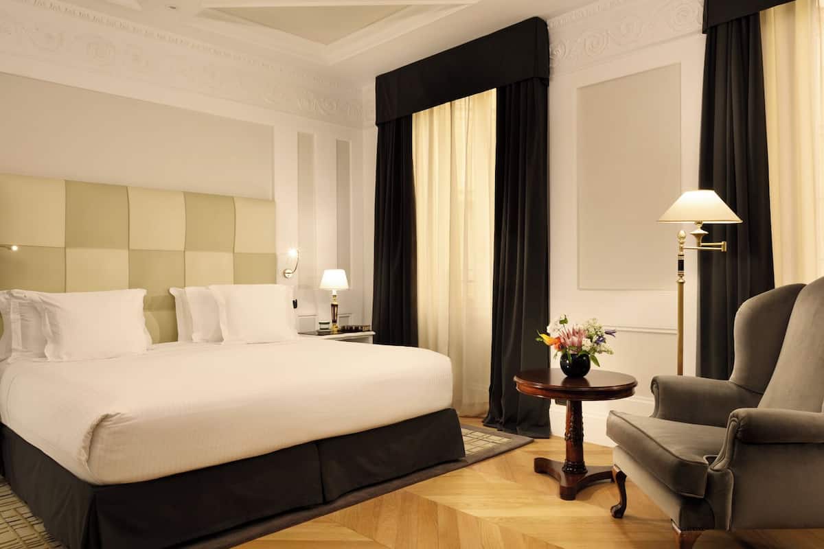 Ein Hotelzimmer mit einem großen Bett, einem Schreibtisch, einem Stuhl und einer Lampe.