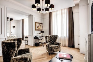 A modern living room with a chandelier, a desk, and a large window with curtains.