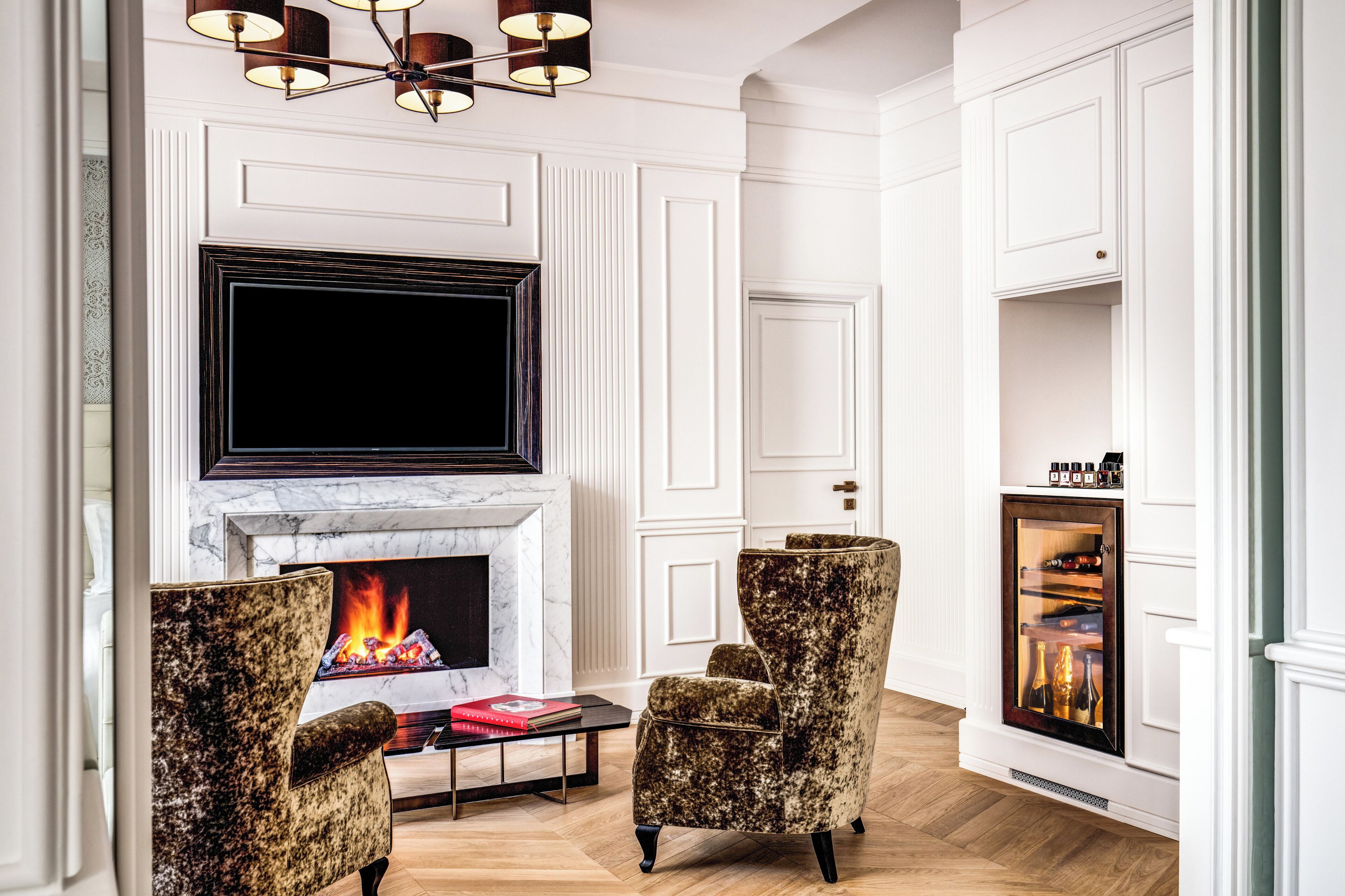 A living room with a fireplace, a television mounted above it, and two armchairs.