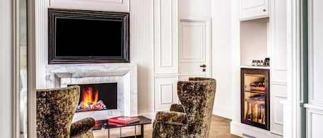 A living room with a fireplace, a television mounted above it, and two armchairs.