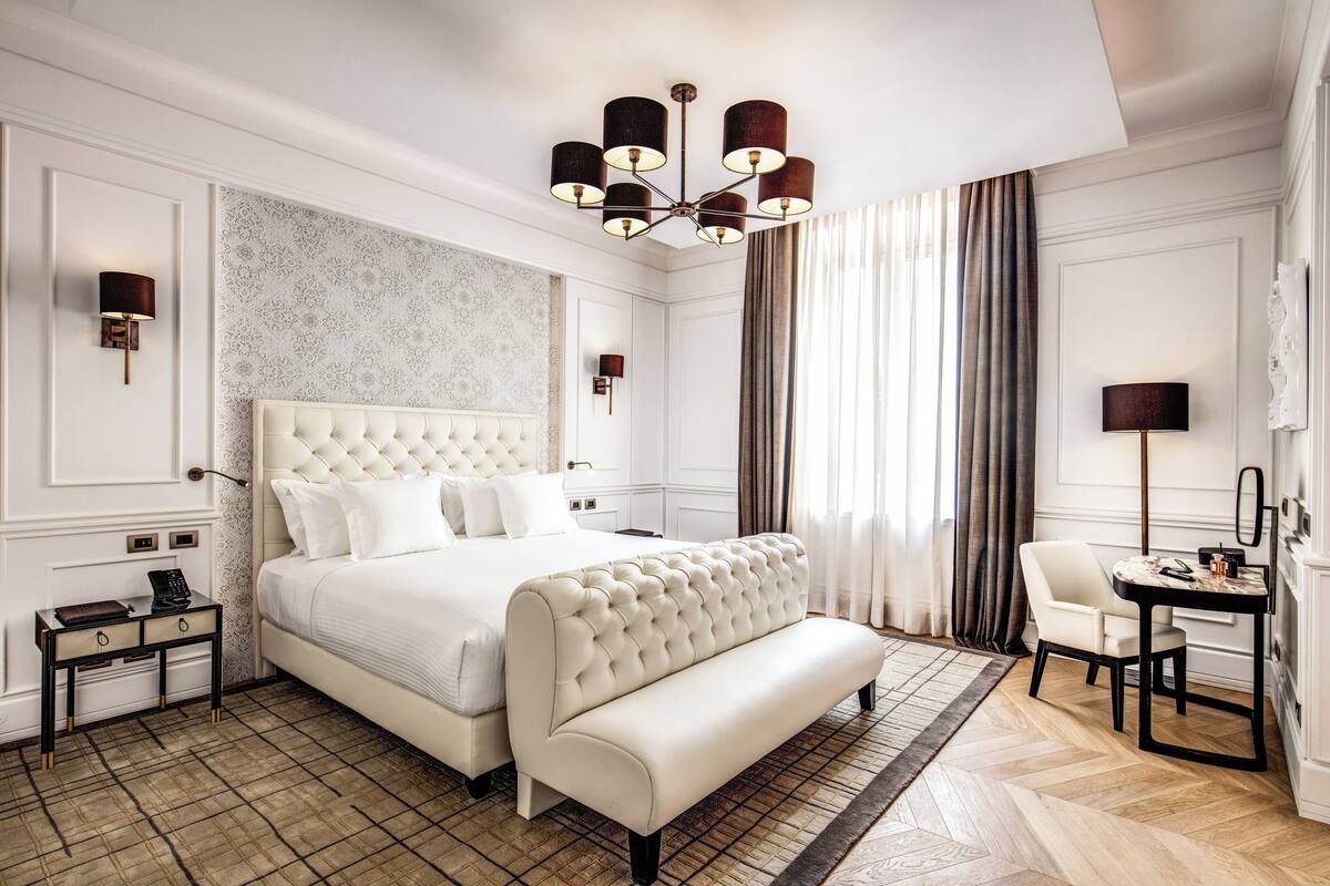 Ein Hotelzimmer mit einem großen Bett, einer Bank, einem Schreibtisch und einem Stuhl.