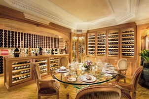 Una cantina vinicola lussuosa, con scaffalature piene di vino, un tavolo da pranzo in vetro e sedie eleganti.