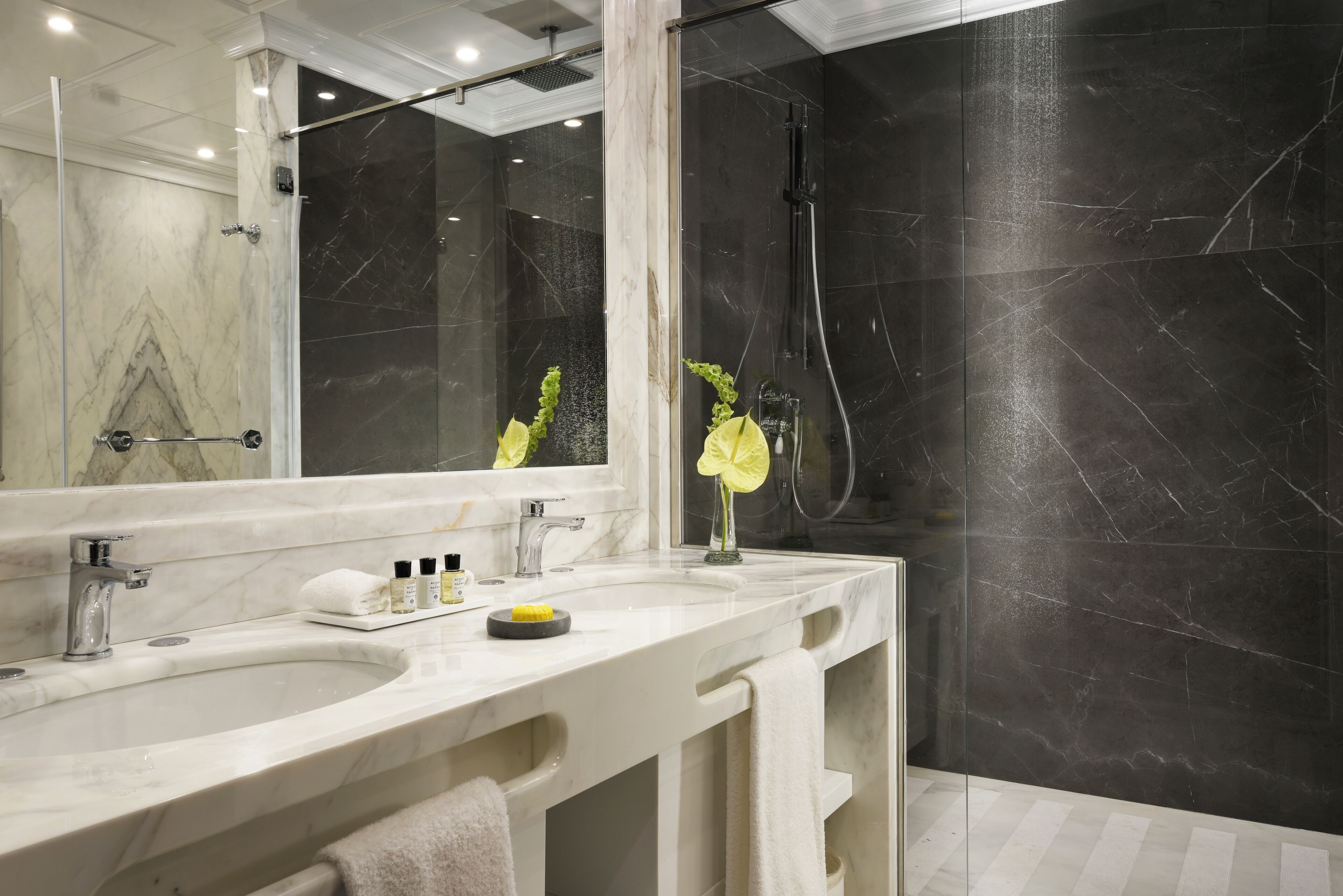Un baño moderno con dos lavamanos, un espejo grande y una zona de ducha.